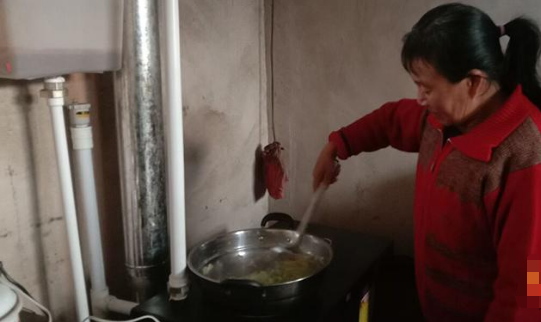 坷台村村民史玉琴正在用生物质取暖炉具做饭